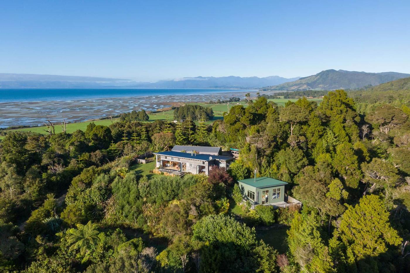 Aerial view of the house in native bush with Farewell Spit beyond