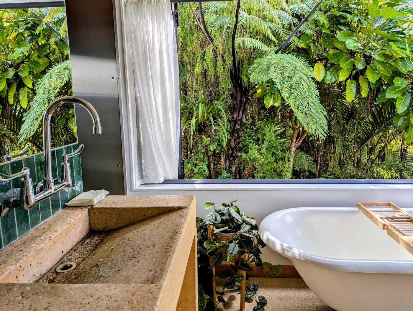 Freestanding bath beside a window onto the bush