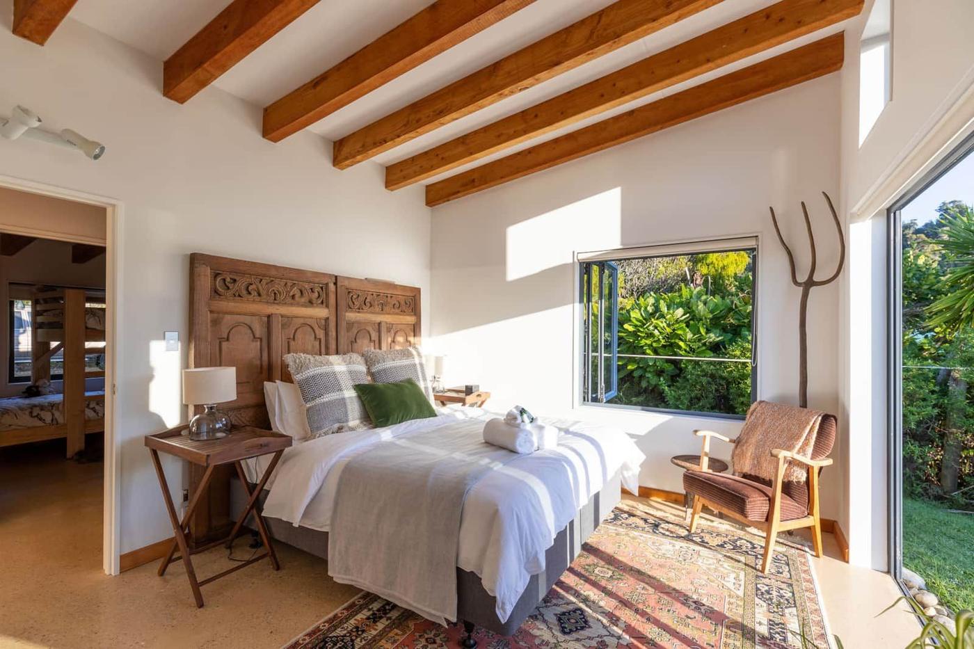 Main bedroom with timber headboard and garden views
