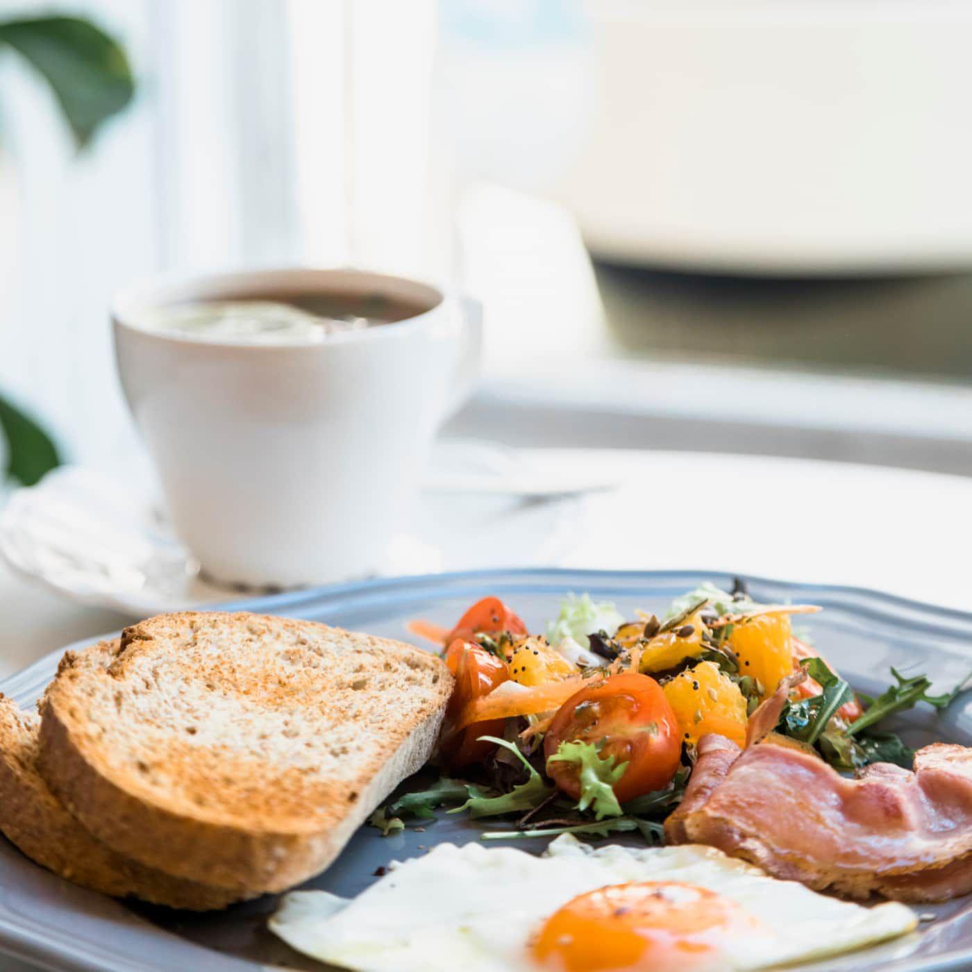 Breakfast of eggs, bacon and toast with coffee