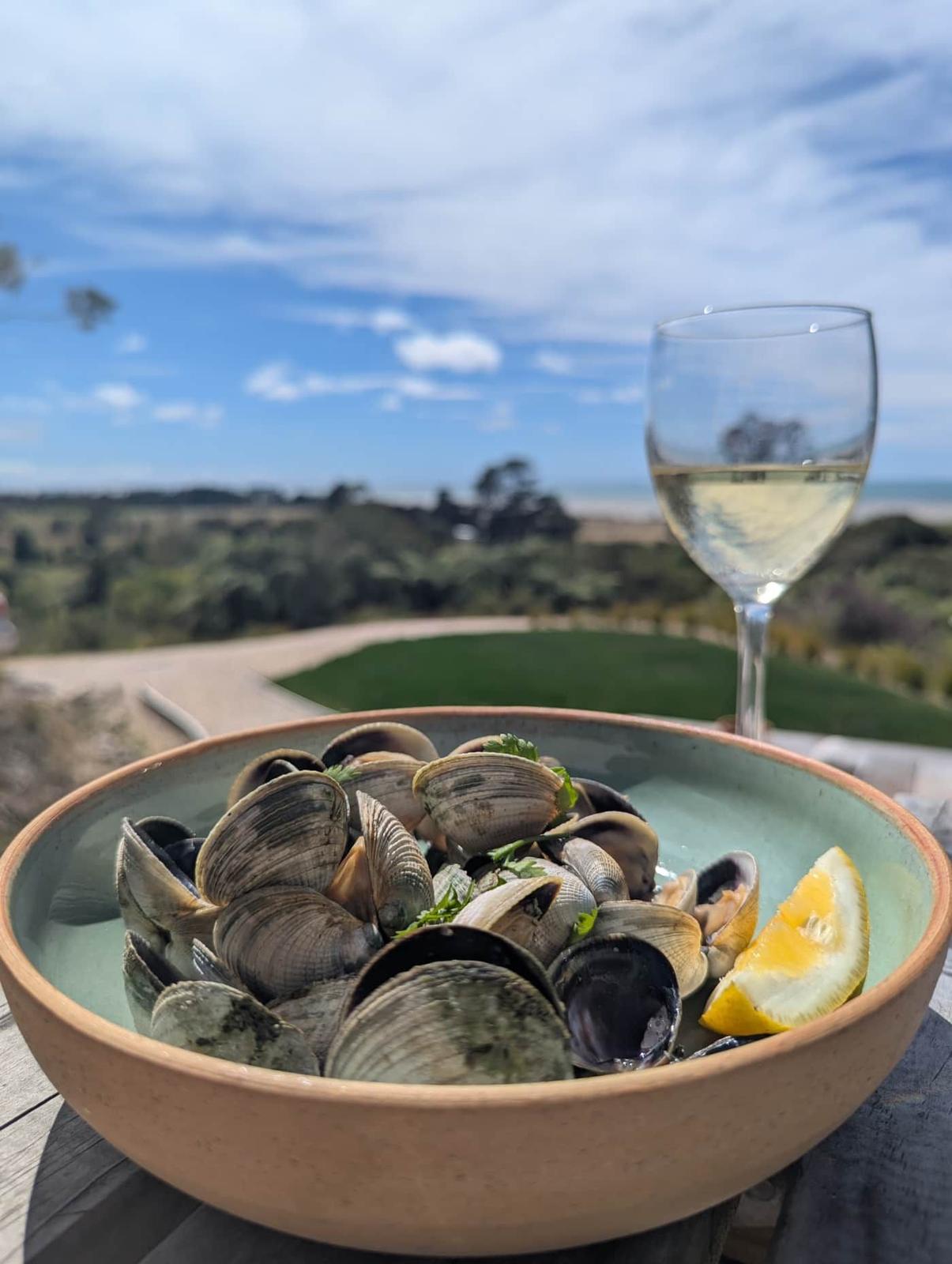 A bowl of freshly cooked cockles with a glass of wine