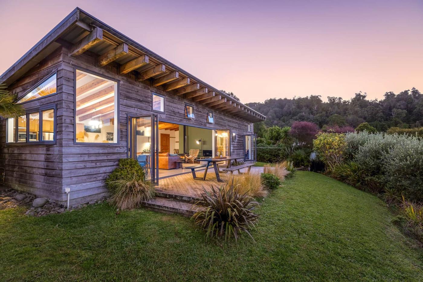 The house at dusk with lights glowing through the windows