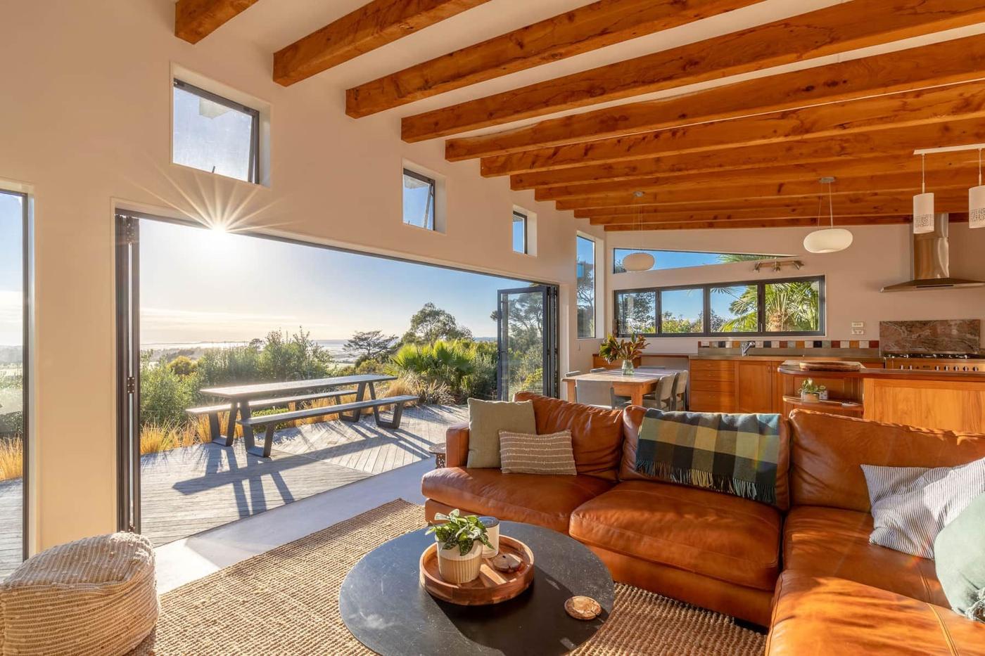 Open-plan living room with timber beams opening to the deck