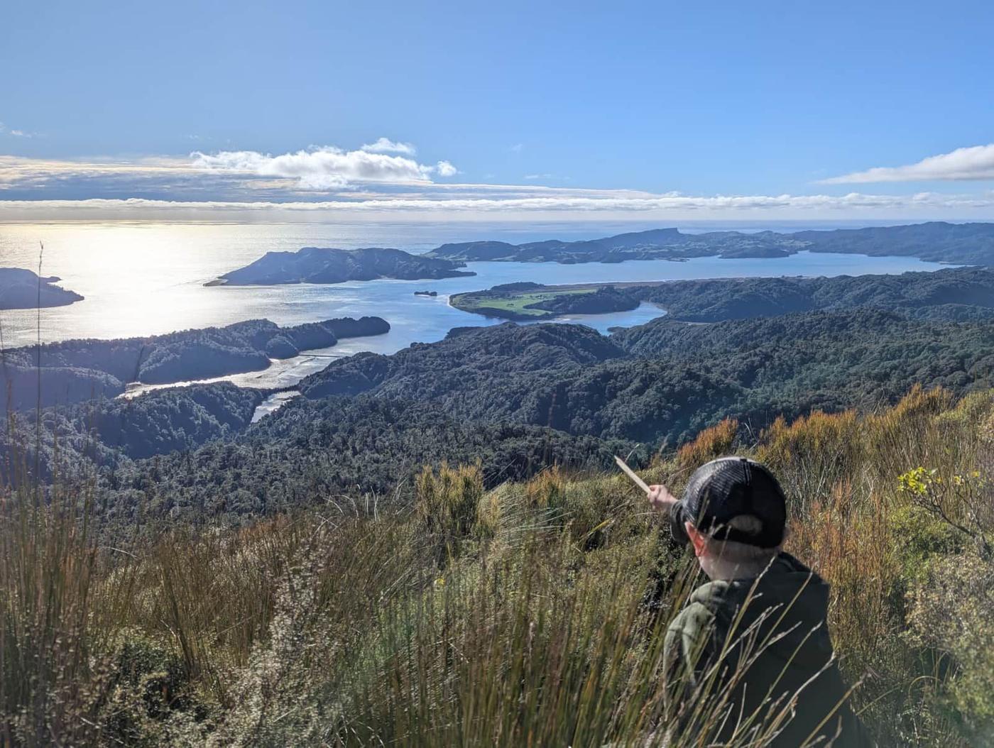 A walker resting on a hilltop above coastal inlets